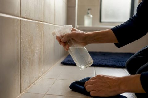 Hands applying vinegar on stained tiles