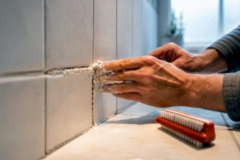 Applying paste to moldy shower grout