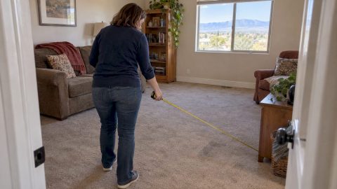 Homeowner measuring room for cleaning estimate