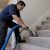 Technician cleaning carpeted stairs with extractor